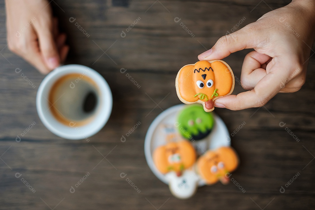 Mão segurando a xícara de café durante comer biscoitos engraçados de Halloween. Feliz dia de Halloween, truque ou ameaça, Olá outubro, outono outono, tradicional, festa e conceito de férias