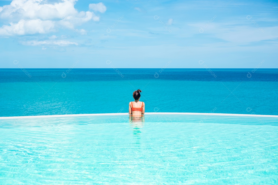 Mulher feliz em maiô laranja nadando na piscina infinita no hotel de luxo contra o mar. jovem fêmea desfrutar em resort tropical. Relaxante, verão, viagens, férias, férias e conceito de fim de semana