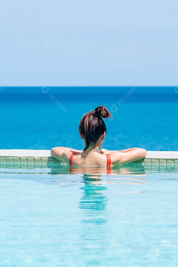 Mulher feliz em maiô laranja nadando na piscina infinita.