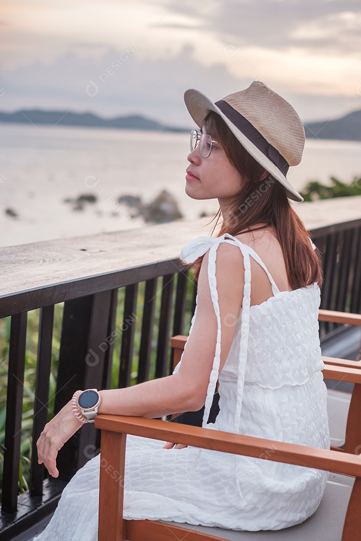 Feliz viajante de vestido branco e chapéu desfruta de um belo mar