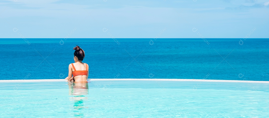 Mulher feliz em maiô laranja nadando na piscina infinita.