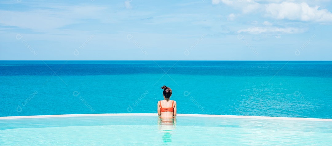 Mulher feliz em maiô laranja nadando na piscina infinita.