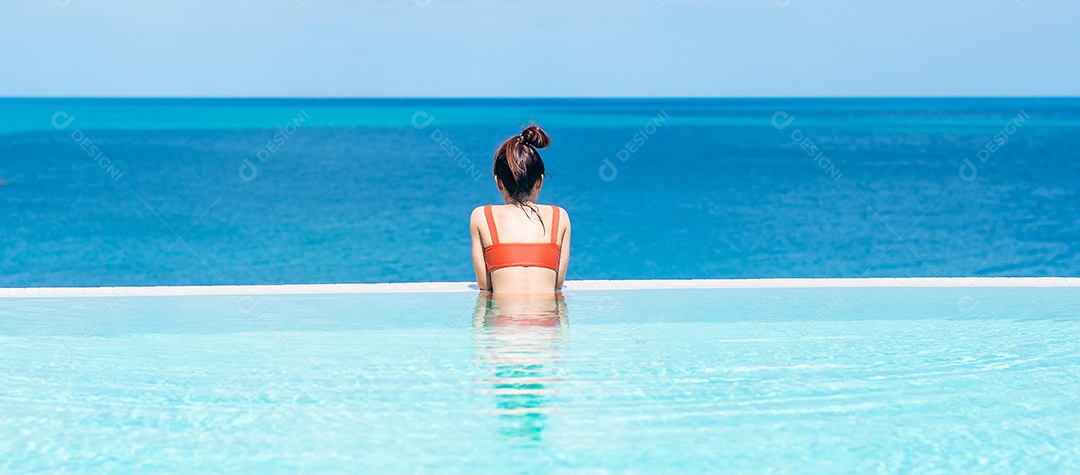 Mulher feliz em maiô laranja nadando na piscina infinita.