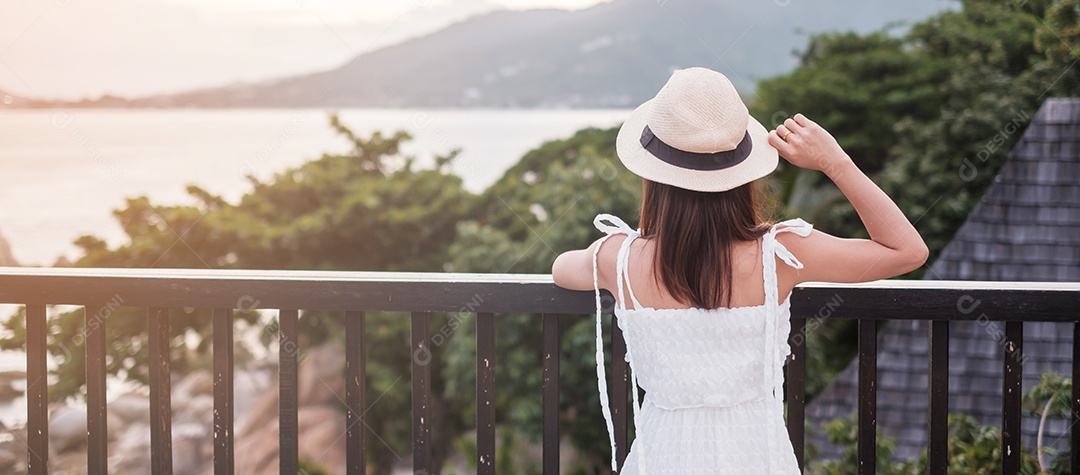 Feliz viajante de vestido branco e chapéu desfruta de um belo mar