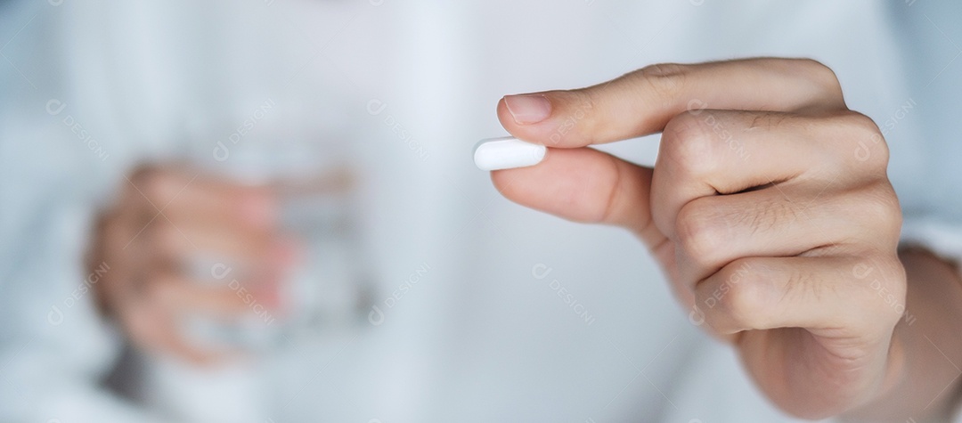 Mulher adulta segurando pílula e copo de água, mulher tomando remédio.