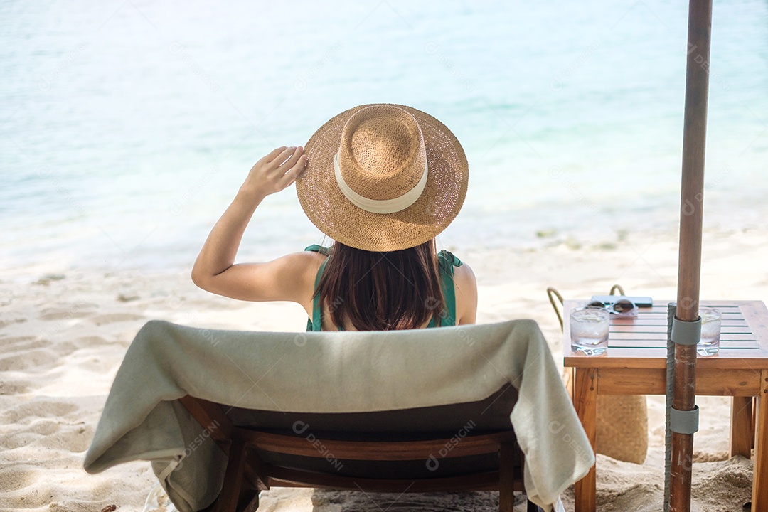 Mulher viajante feliz em trajes de banho verdes e chapéu desfruta.