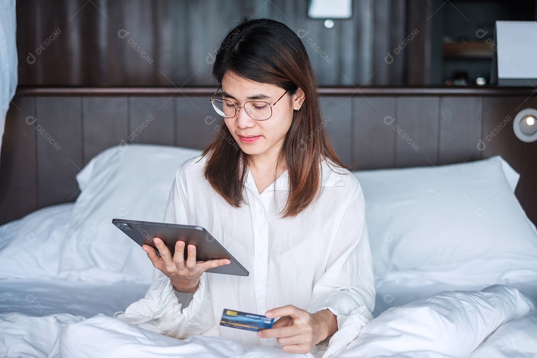 Mulher usando tablet e cartão de crédito para compras online.