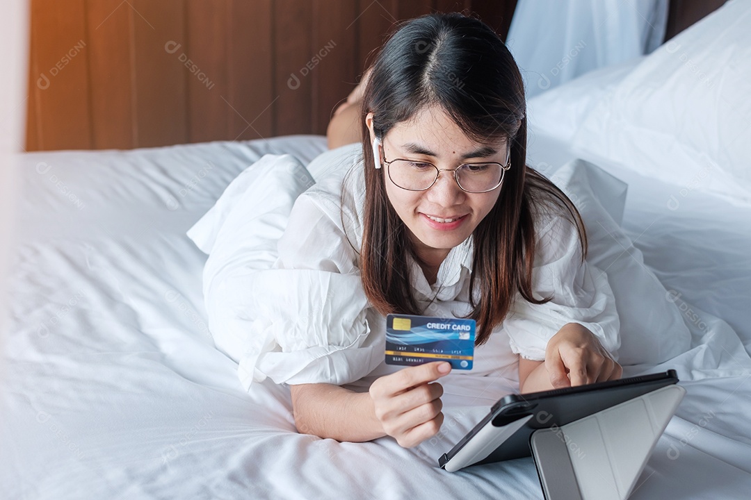 Mulher usando tablet e cartão de crédito para compras online.