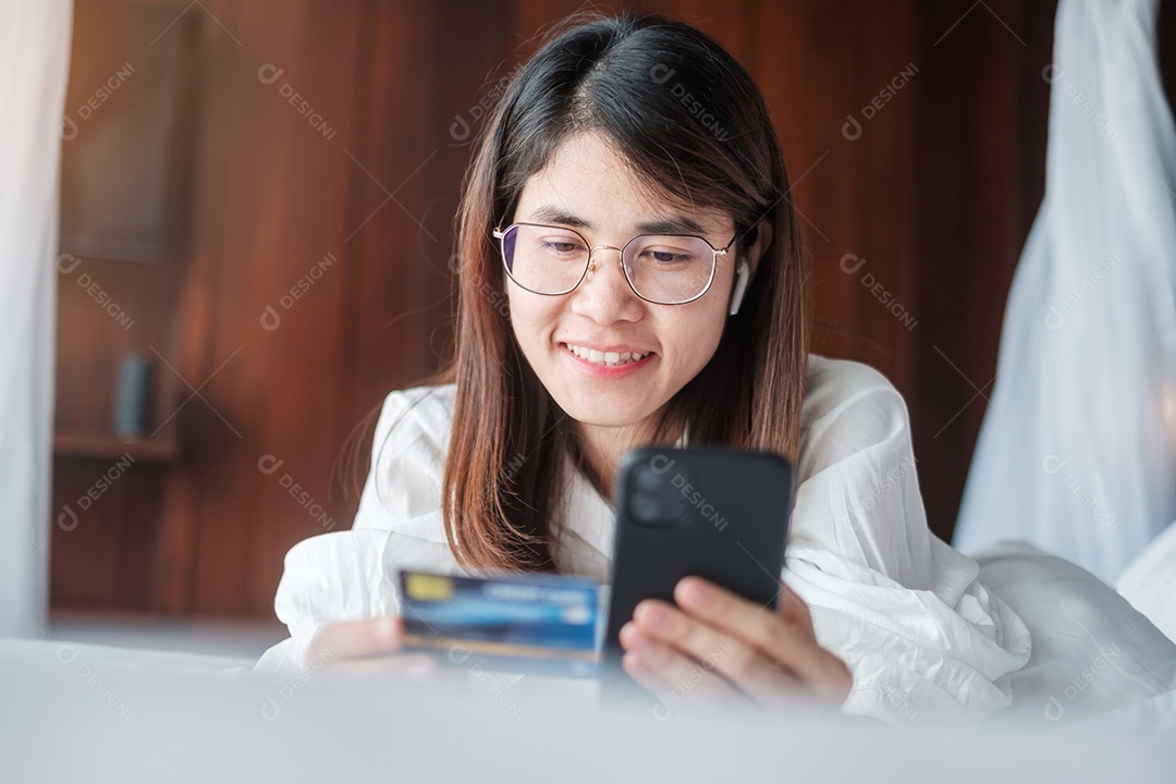 Mulher usando telefone inteligente móvel e cartão de crédito para compras online