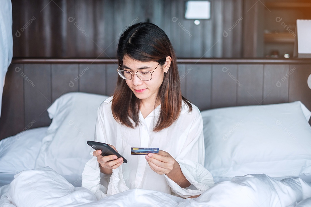 Mulher usando telefone inteligente móvel e cartão de crédito para compras online.