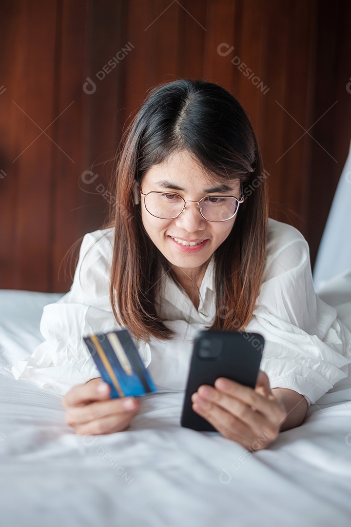 Mulher usando telefone inteligente móvel e cartão de crédito para compras online.