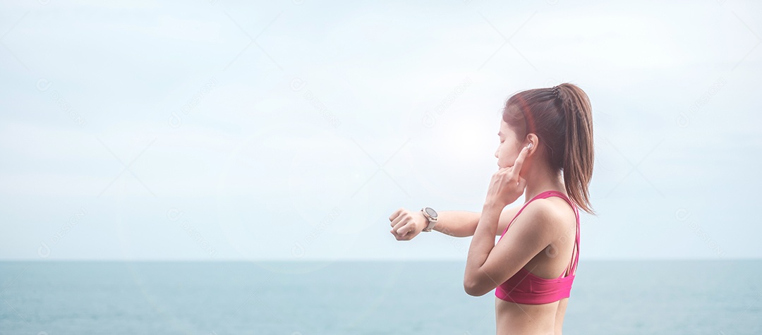 Fêmea jovem fitness em roupas esportivas esticando o corpo contra o oceano.