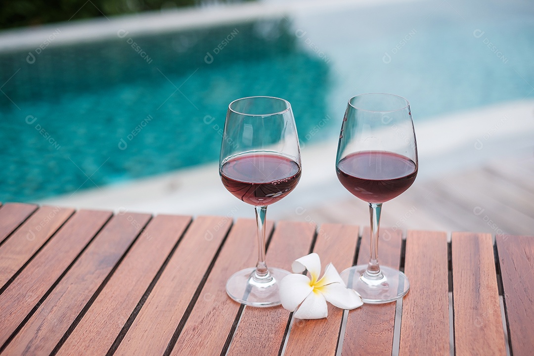 Dois copos de vinhos tintos perto da piscina. Viagens de verão, férias, férias e conceito de fim de semana feliz