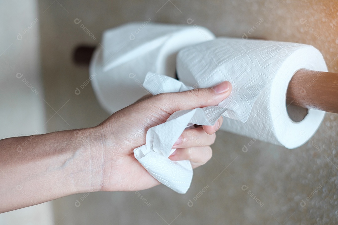 Mão de mulher puxando papel higiênico no banheiro. Limpeza, estilo de vida.