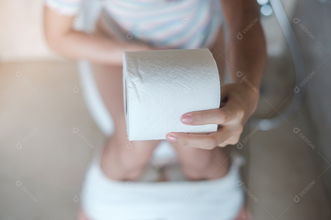 Mulher segurando rolo de papel higiênico durante sentar no vaso sanitário.