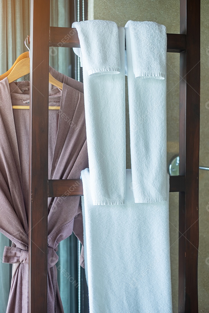 Close-up roupão de banho limpo e toalha pendurada no guarda-roupa de madeira.
