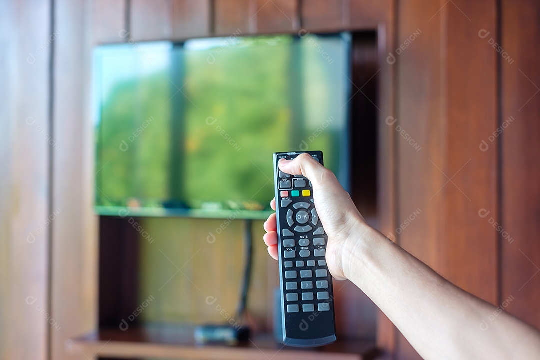 Mão usando o controle remoto para ajustar a TV dentro do modo.