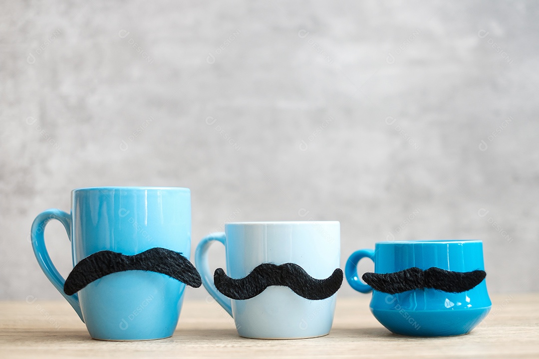 Xícara de café azul e caneca de chá com decoração de bigode preto em madeira.