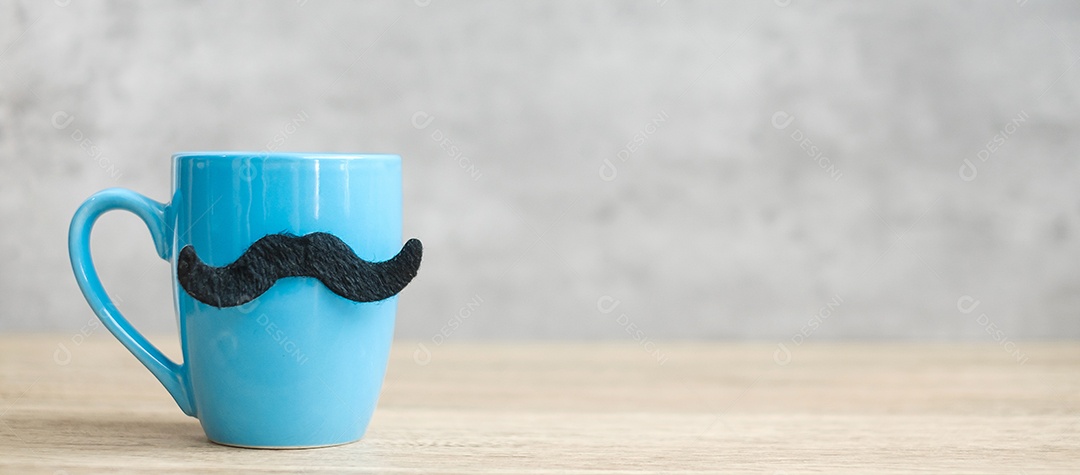 Xícara de café azul ou caneca de chá com decoração de bigode preto na mesa.