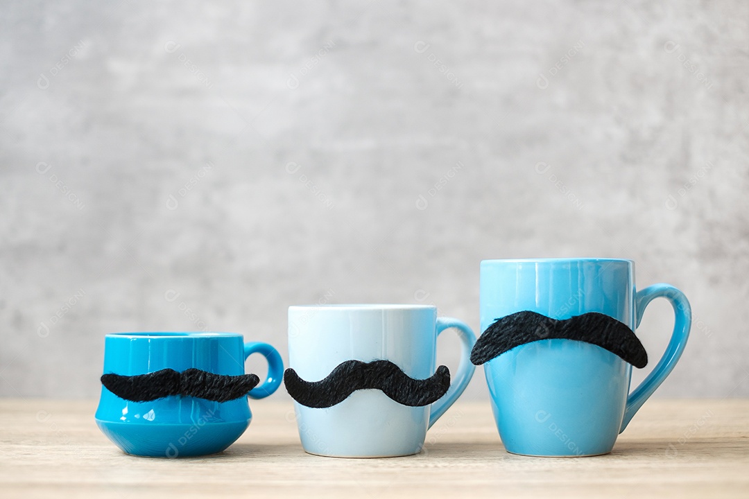 Xícara de café azul e caneca de chá com decoração de bigode preto em madeira.