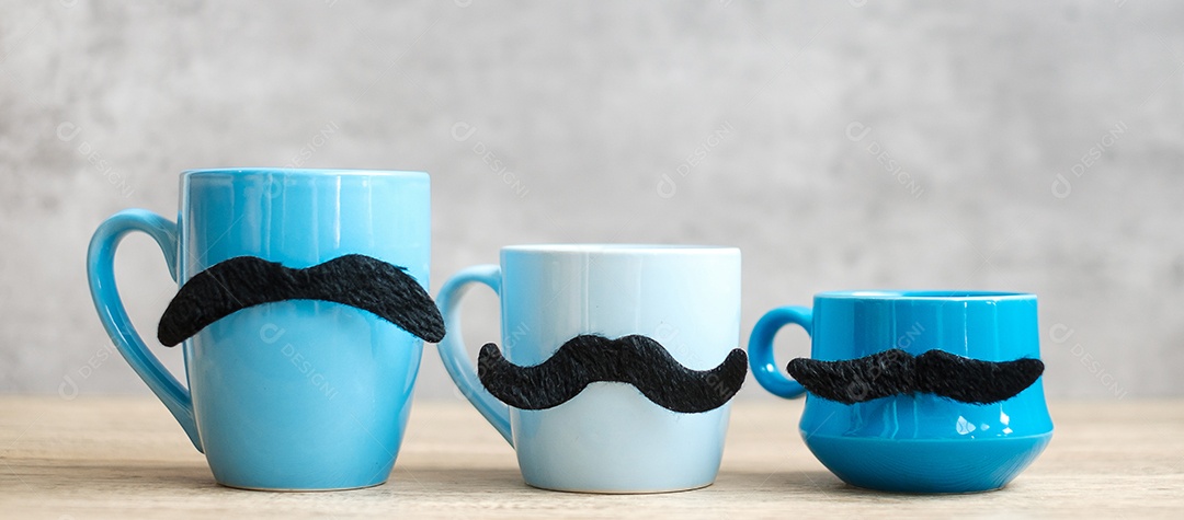 Xícara de café azul e caneca de chá com decoração de bigode preto em madeira.