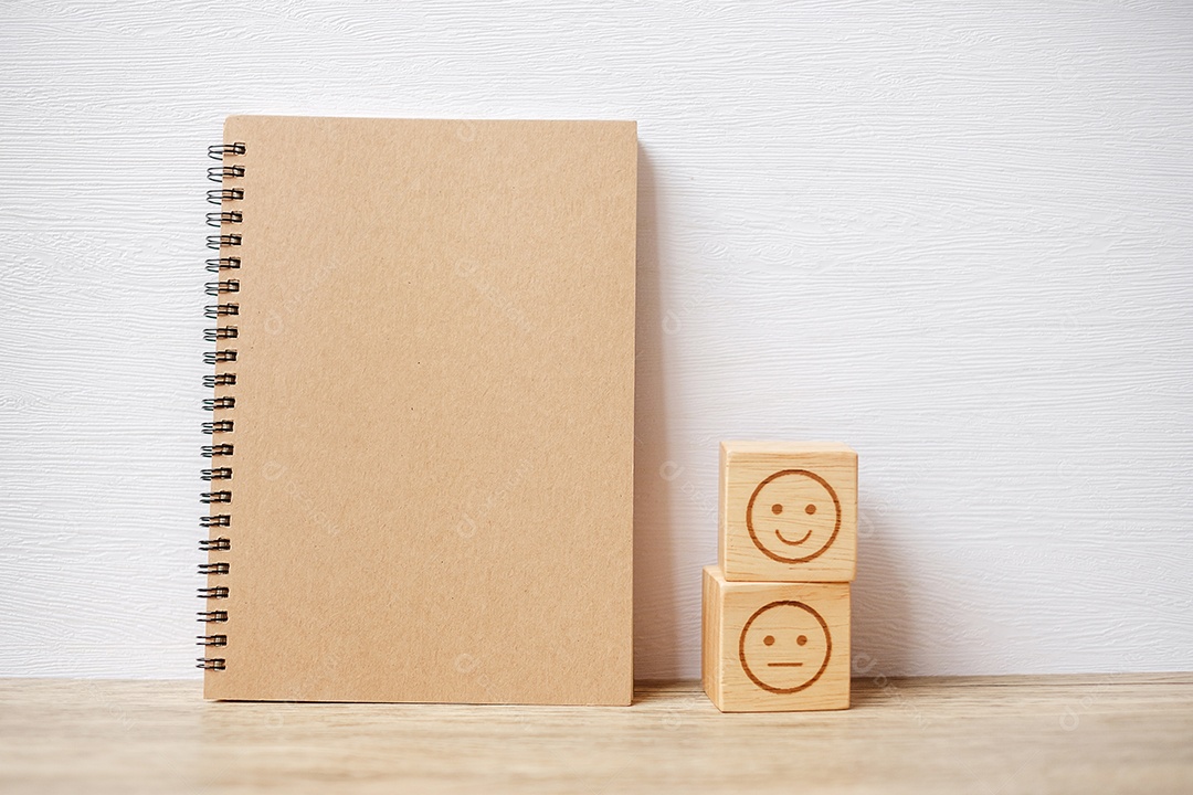 Bloco de rosto de emoção e notebook na mesa. Emoticon para cliente.