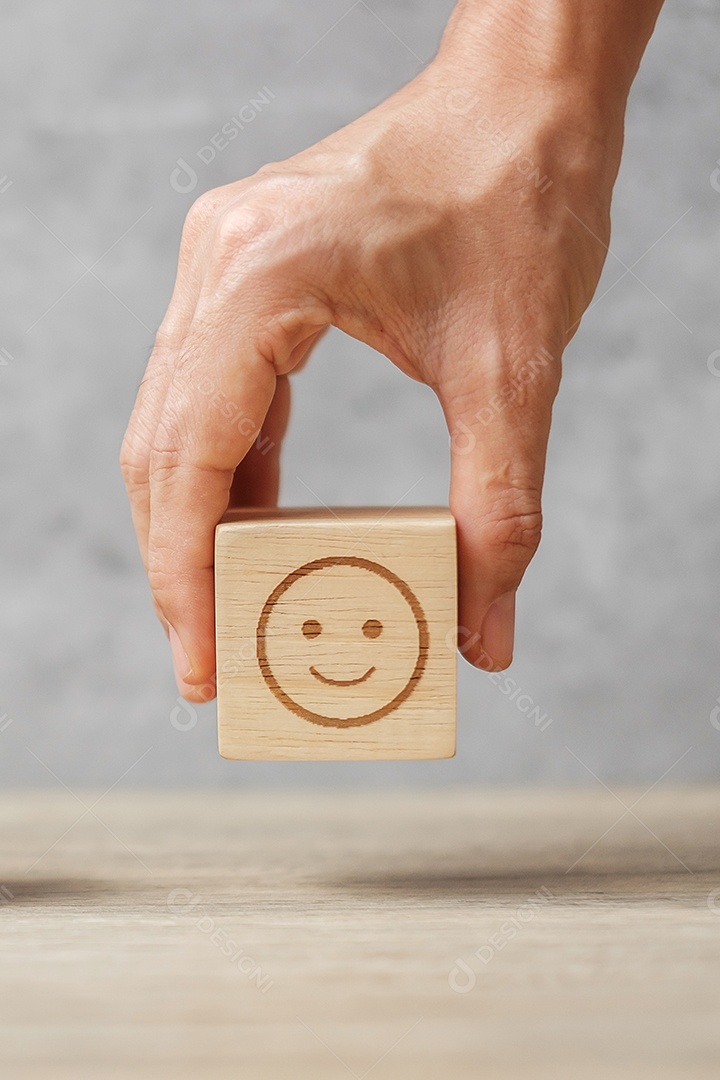Mão segurando o bloco de rosto de sorriso. O cliente escolhe o Emoticon para o usuário