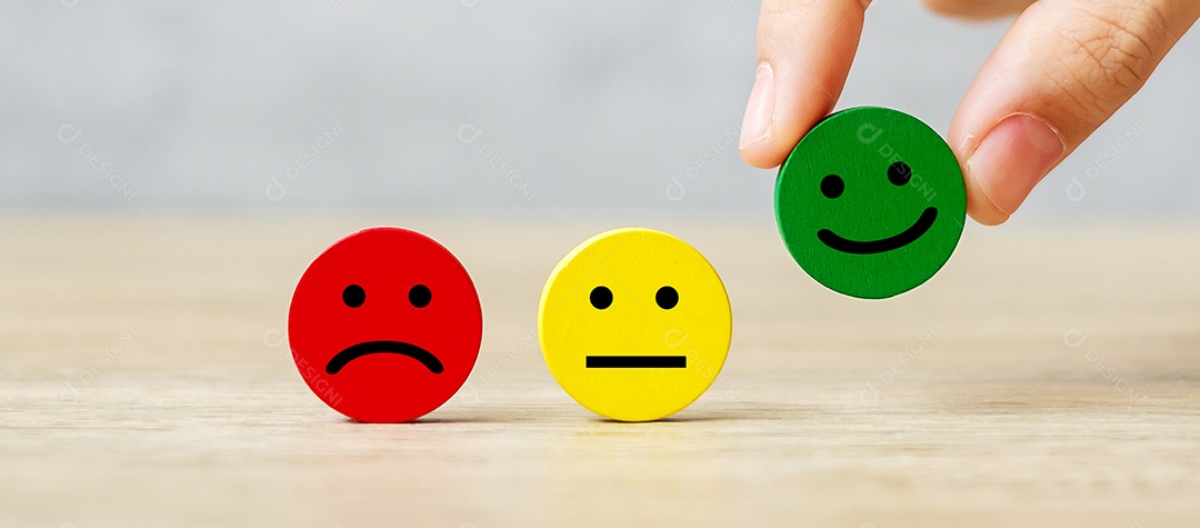 Mão segurando o bloco de rosto de emoção. O cliente escolhe o Emoticon para nós.