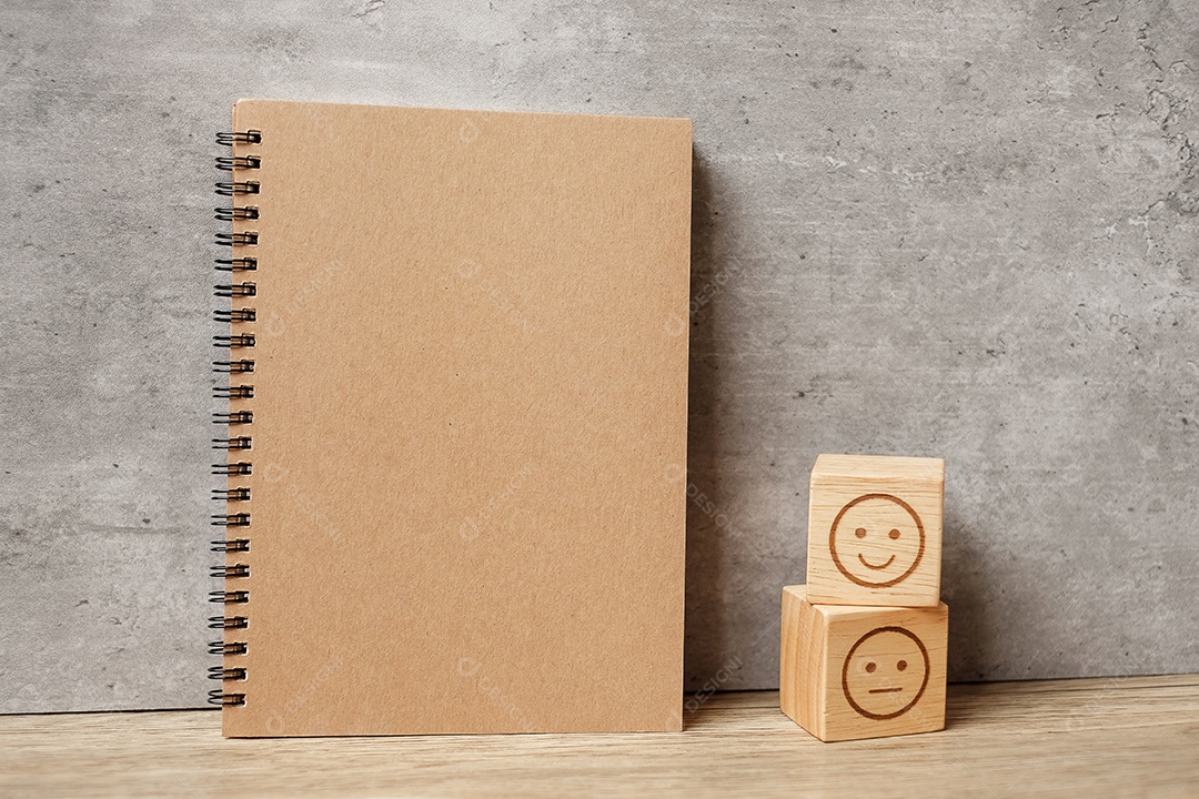 Bloco de rosto de emoção e notebook na mesa. Emoticon para cliente.