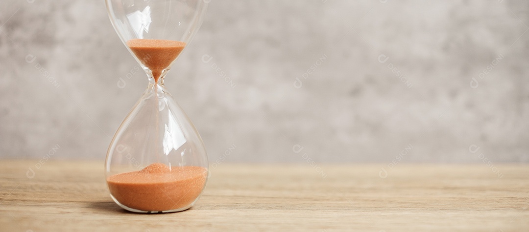 Ampulheta na mesa, areia fluindo através do bulbo.