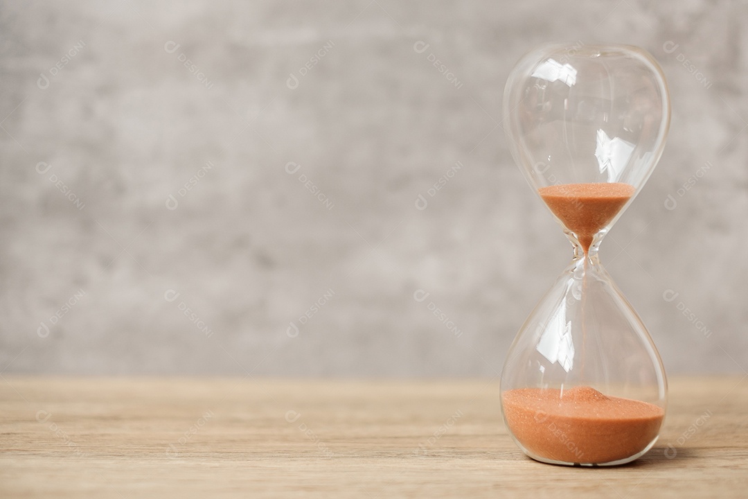 Ampulheta na mesa, areia fluindo através do bulbo.