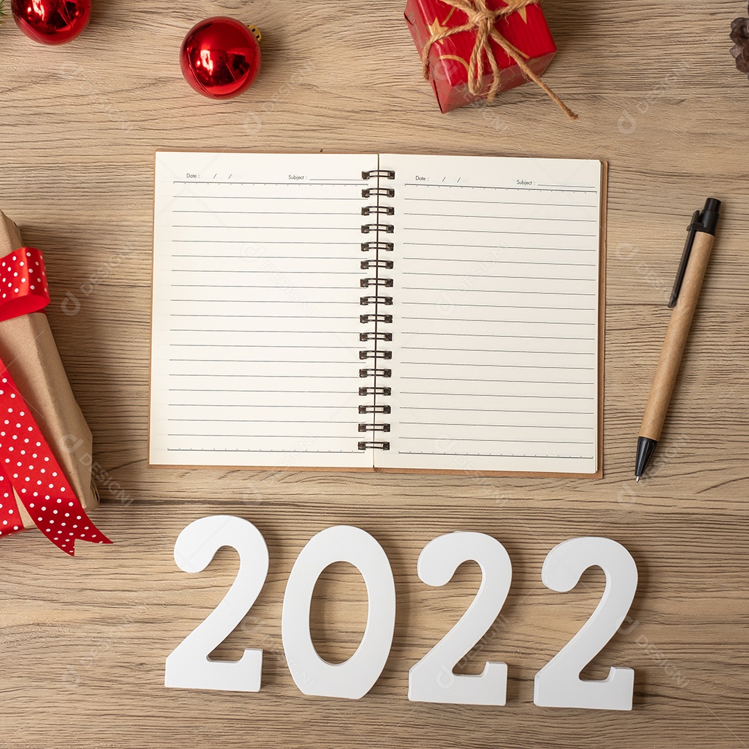 2022 Ano Novo com notebook, presente de Natal e caneta na mesa de madeira.