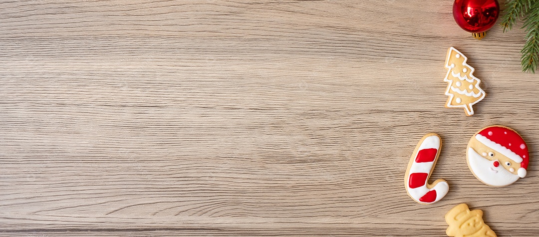 Feliz Natal com biscoitos caseiros e xícara de café na aba de madeira.