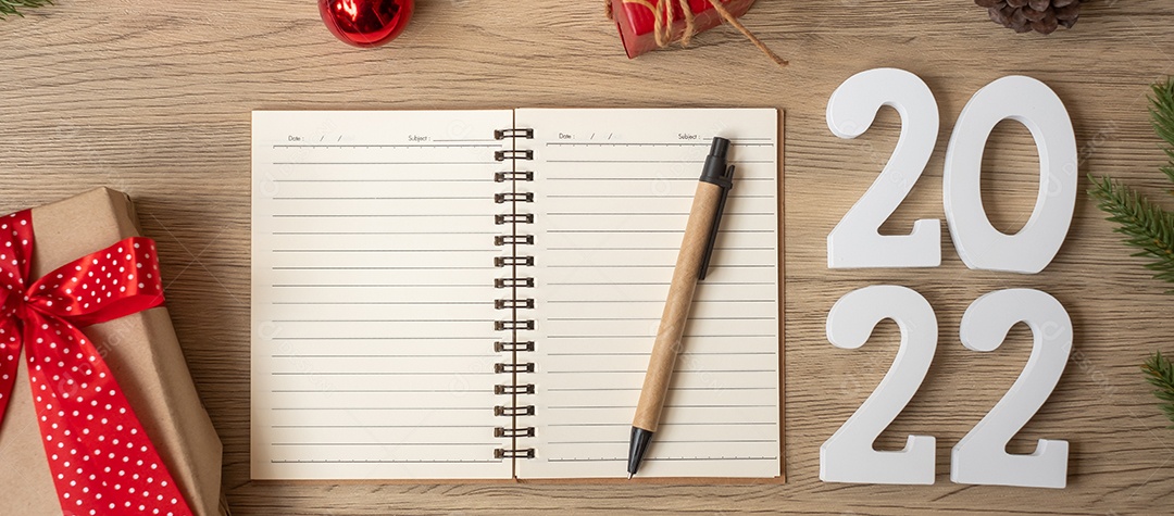 2022 Ano Novo com notebook, presente de Natal e caneta na mesa de madeira.