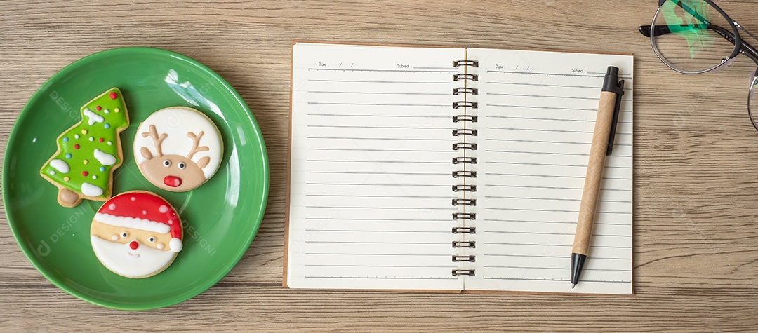 Caderno em branco, preto, biscoitos de Natal e caneta na mesa de madeira