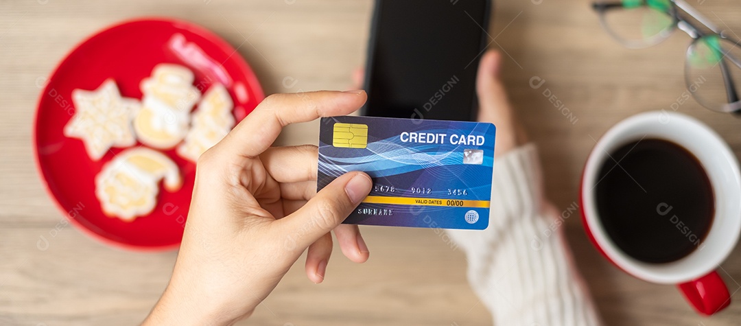 Mão segurando o cartão de crédito para compras online no smartphone