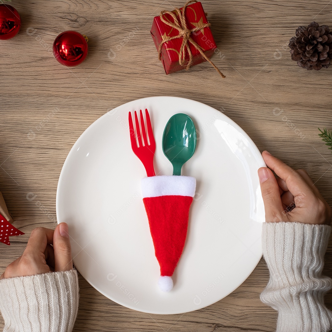 Feliz Natal com a mão da mulher segurando o prato, garfo e colher.