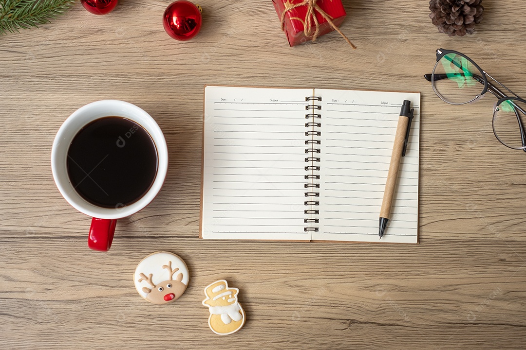 Caderno em branco, xícara de café preto, biscoitos de Natal e caneta.