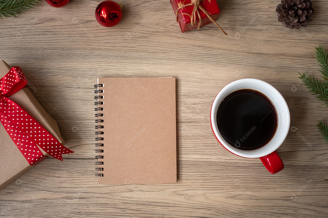 Caderno em branco, xícara de café preto e presente de Natal na mesa de madeira.