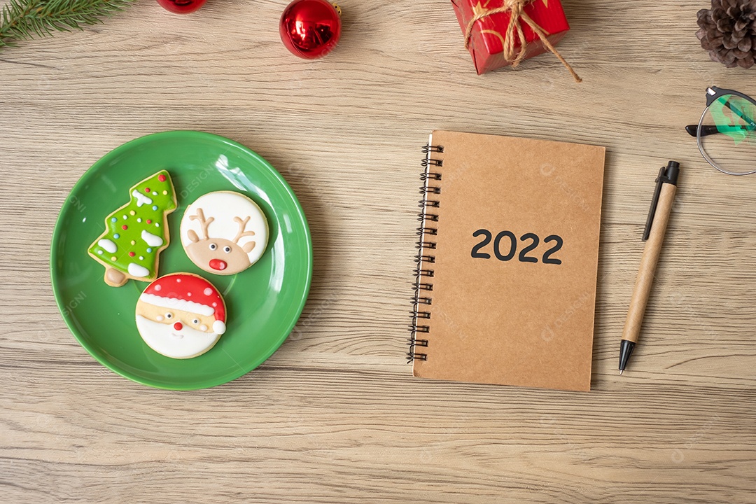 2022 notebook, preto, biscoitos de Natal e caneta na mesa de madeira.