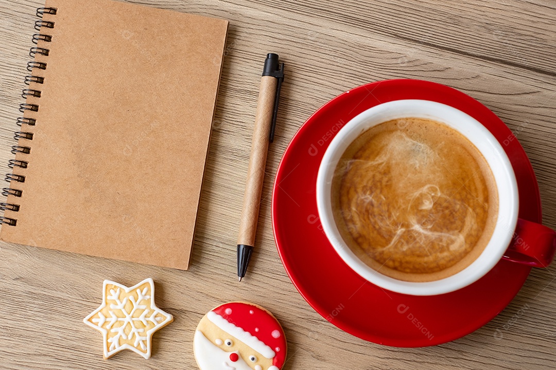 Caderno em branco, xícara de café preto, biscoitos de Natal e caneta.