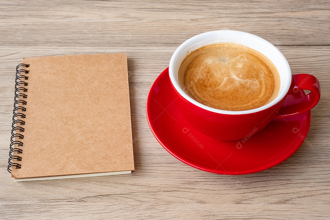 Caderno em branco e xícara de café na mesa de madeira. Motivação, determinação.