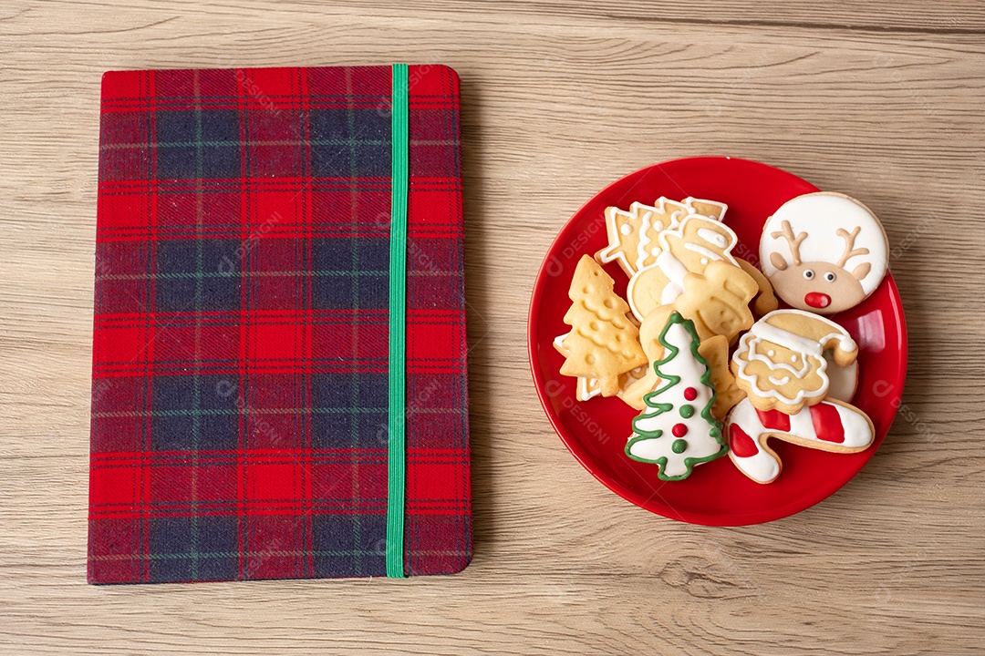 Caderno em branco, biscoitos de Natal e caneta na mesa de madeira.