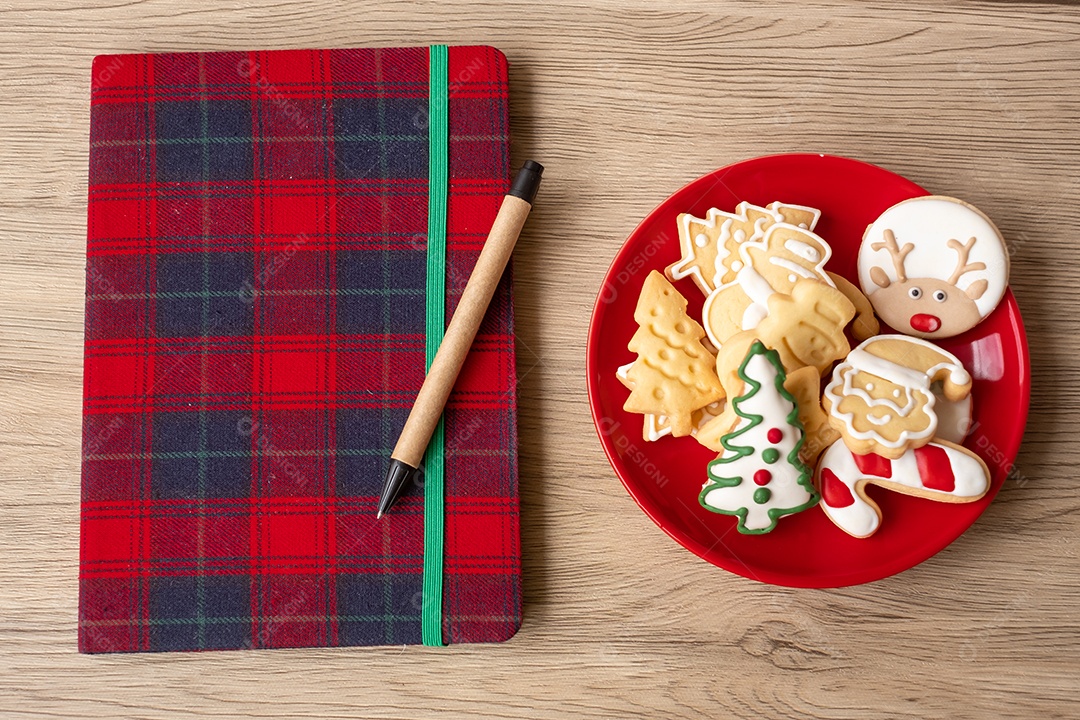 Caderno em branco, biscoitos de Natal e caneta na mesa de madeira.