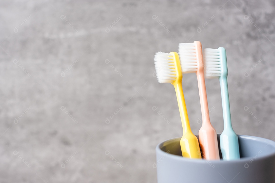 Conjunto de escovas de dentes no copo no fundo da parede no banheiro.