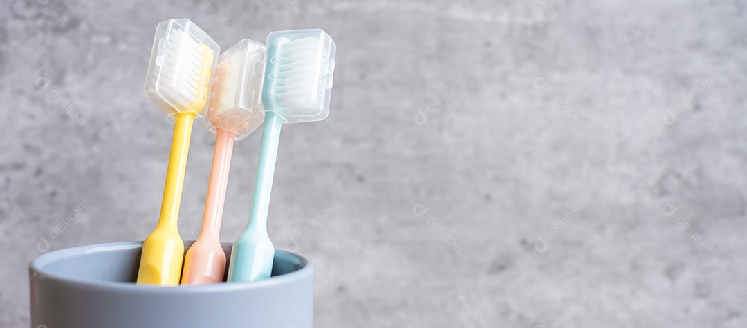 Conjunto de escovas de dentes no copo no fundo da parede no banheiro.