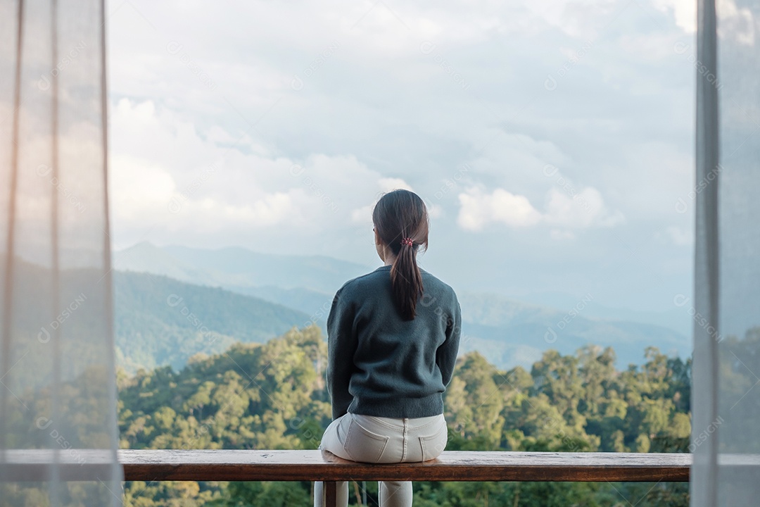 Mulher feliz relaxando e olhando a vista para a montanha no campo.