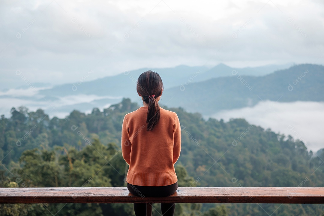 Mulher feliz relaxando e olhando a vista para a montanha no campo.