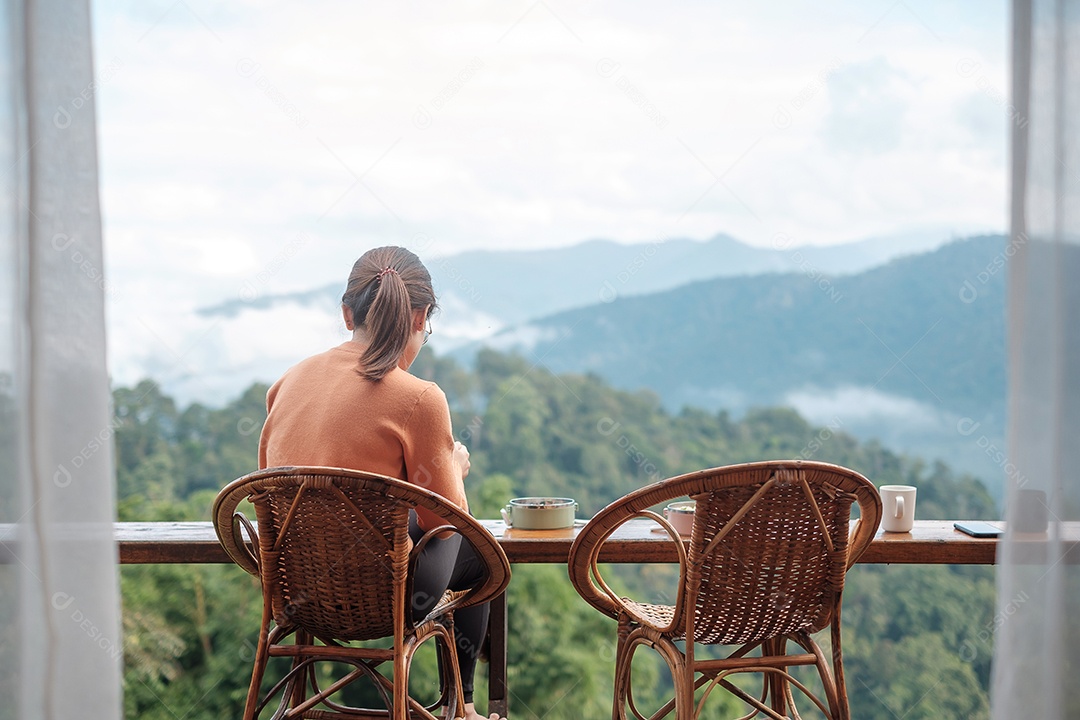 Mulher feliz tomando café e tomando café da manhã contra a montanha