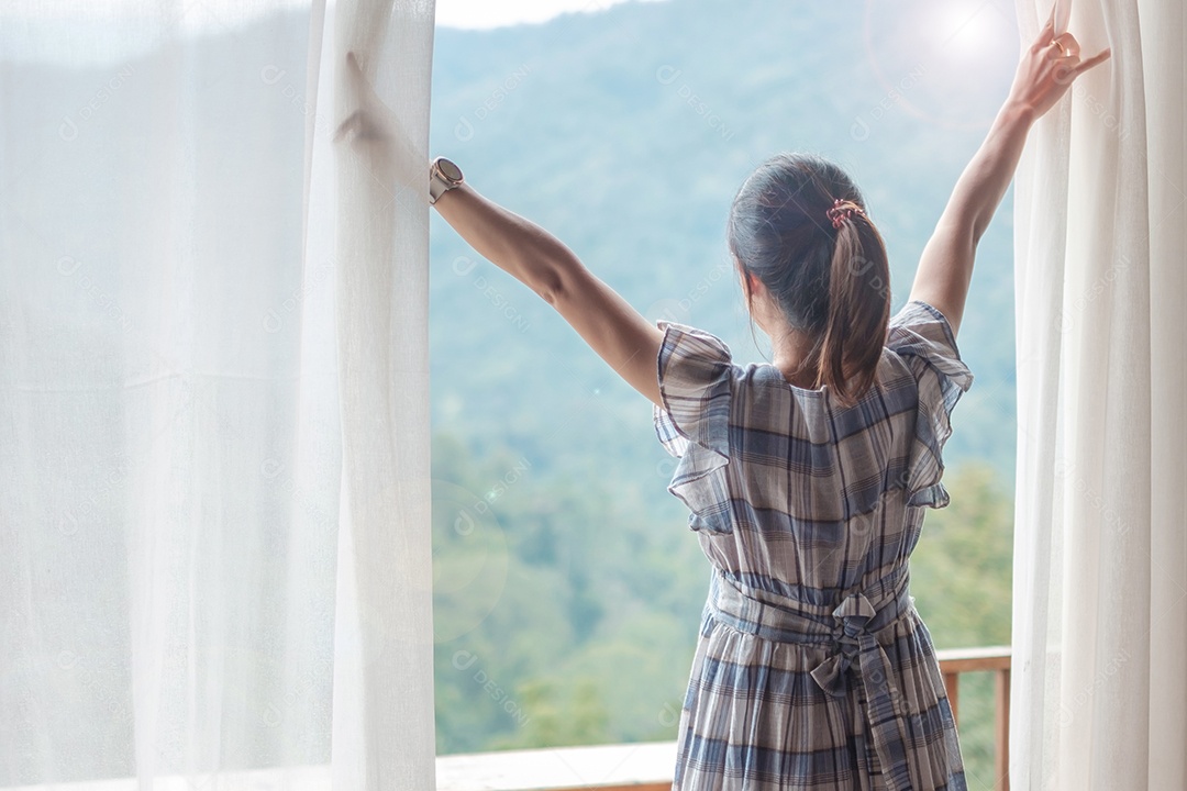 Mulher feliz, estendendo-se perto da janela, jovem adulta feminina.